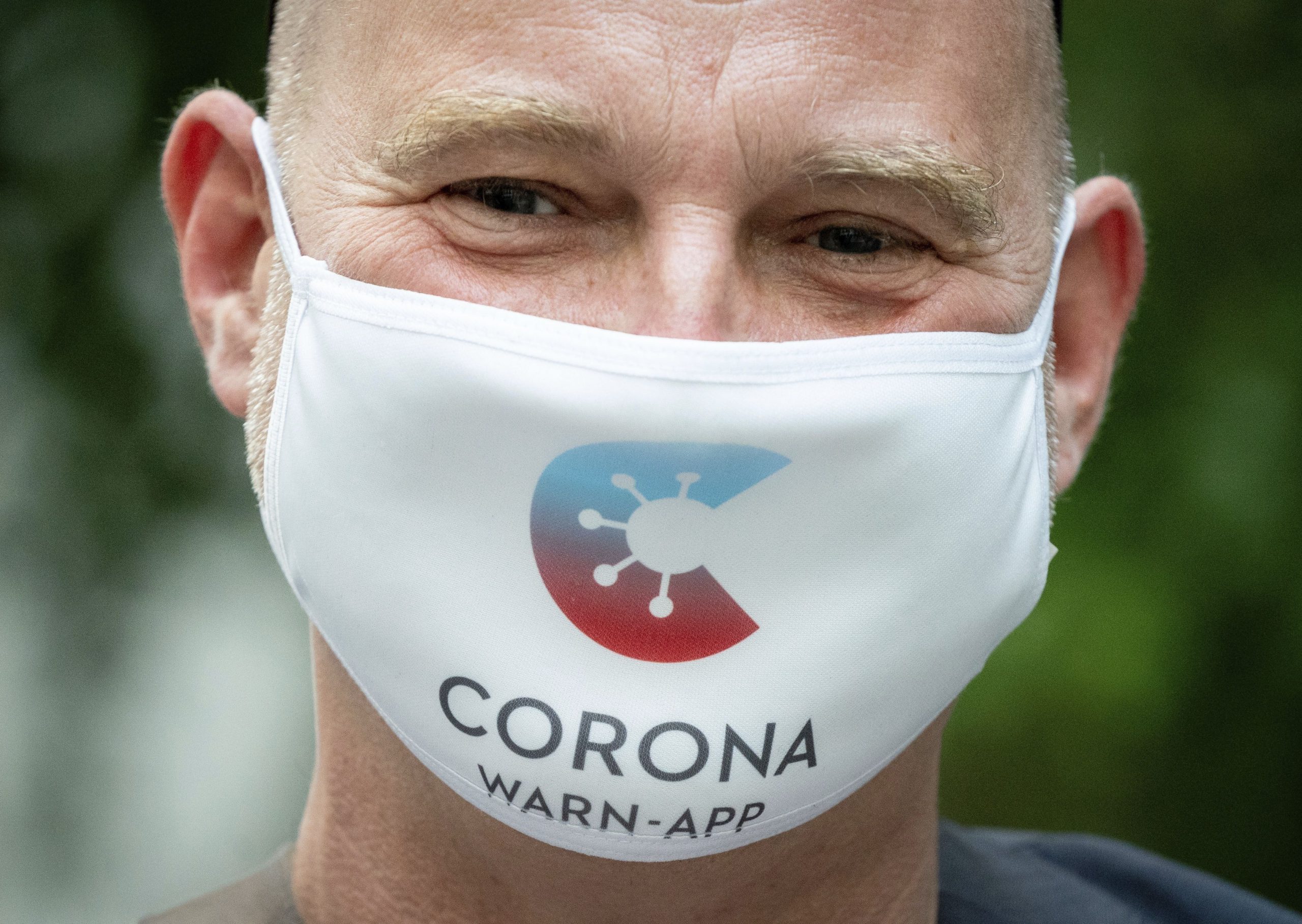 Rainer Knirsch, Telekom press spokesman, wears a mouth and nose protector with the app's logo at the beginning of a press conference on the 100-day Corona Warning App at the Federal Press Conference Center in Berlin, Germany, Wednesday, Sept. 23, 2020.(Kay Nietfeld/dpa via AP)