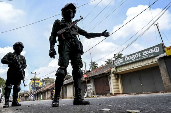 Security personnel gesture to stop motorists at a checkpoint in Divulapitiya on the outskirts of the Sri Lankan capital of Colomb. Photographer: Ishara S. Kodikara/AFP/Getty Images